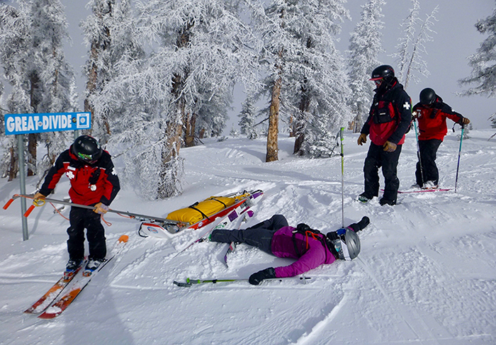 Rachel Weinzimmer, portraying a skier laid out with a neck injury, training new ski-patrol personnel on medical assessment and treatment