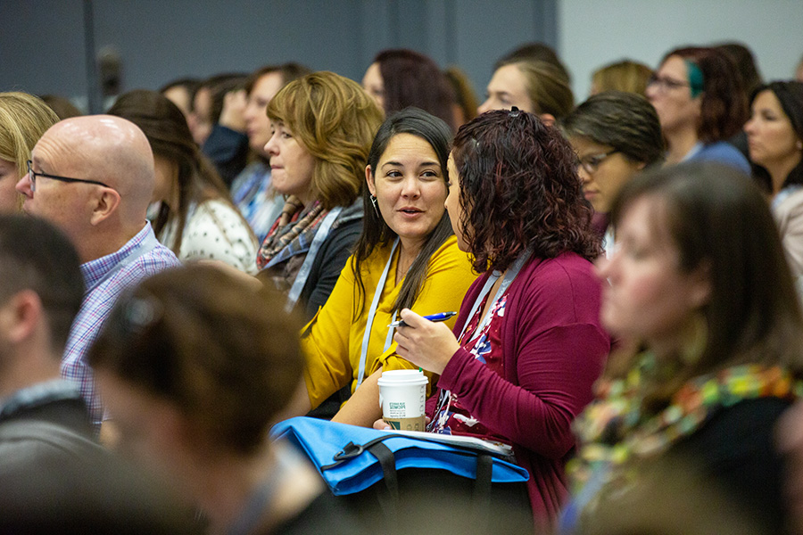 Two women sitting in audience chatting